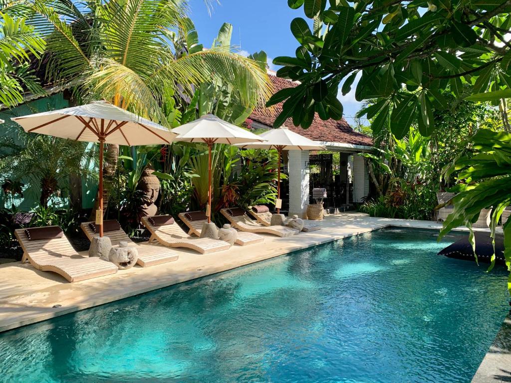 a pool with chairs and umbrellas in a resort at Hari Indah Boutique Hotel & Spa in Uluwatu