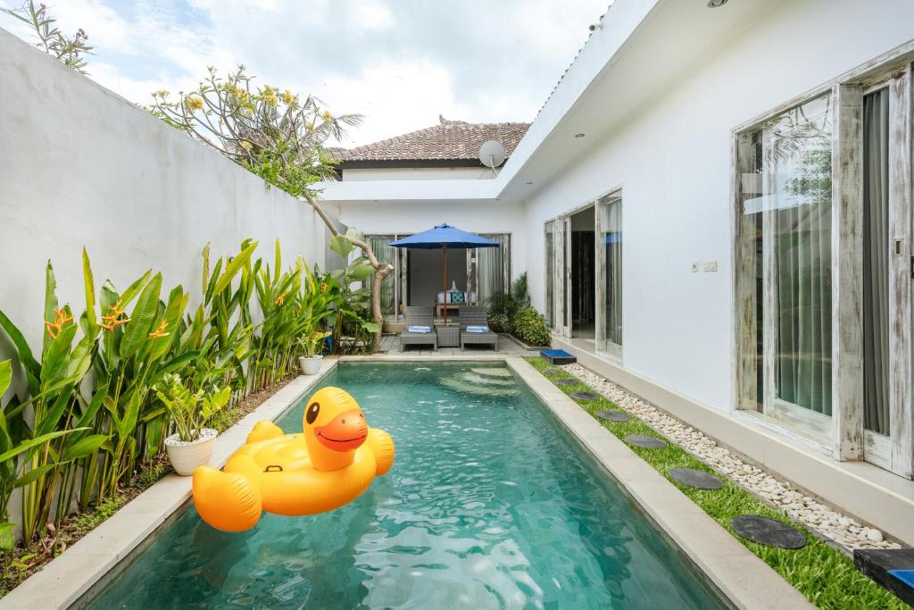 una piscina en el patio trasero de una casa con dos patos de goma en el agua en Villa Cathy, en Seminyak