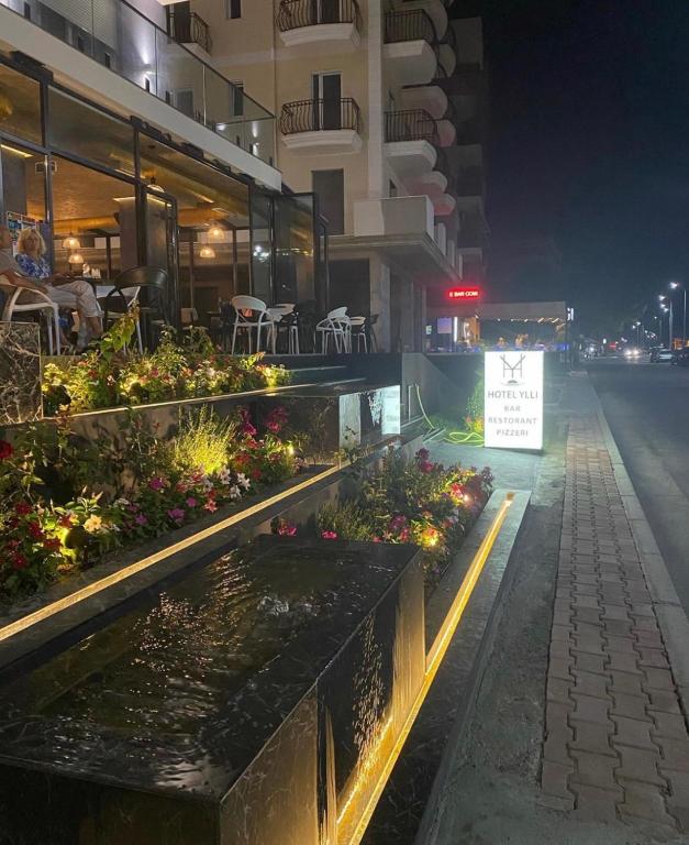 a restaurant with a pond in the street at night at HOTEL BAR RESTORANT YLLI in Shëngjin