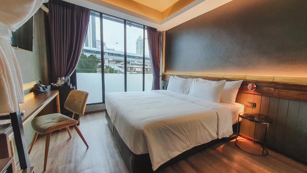 a hotel room with a bed and a large window at Hotel Ordinary Bangkok in Bangkok