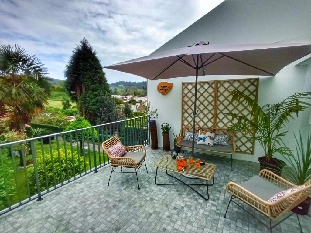 a patio with chairs and an umbrella and a table at Casa Pacheco in Furnas
