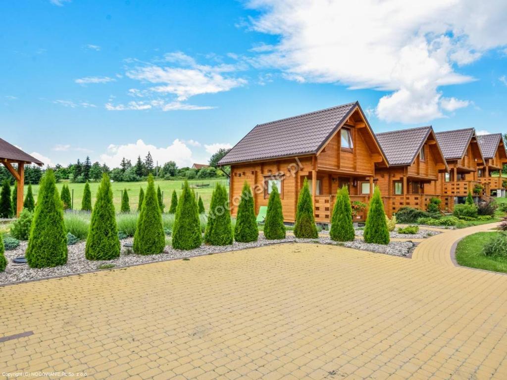 drewniany dom z dziedzińcem i drzewami w obiekcie Całoroczne Domki Zaciszna Polana w Polanicy Zdroju