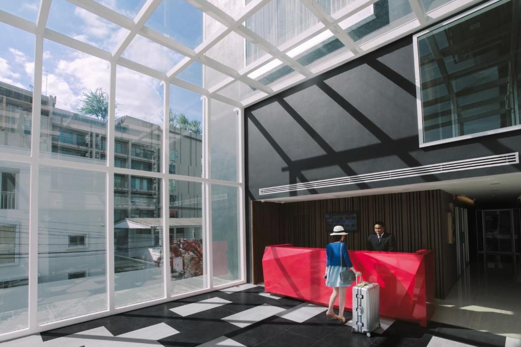 une femme debout à l'extérieur d'un bâtiment avec ses bagages dans l'établissement Olive Bangkok Hotel, à Bangkok