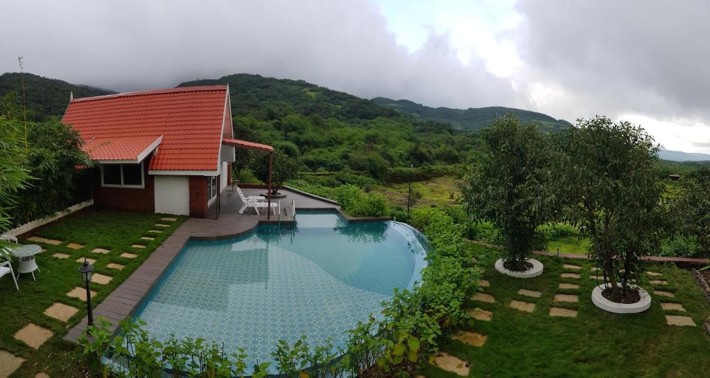 a swimming pool in front of a house with a mountain at Nostravila in Lonavala