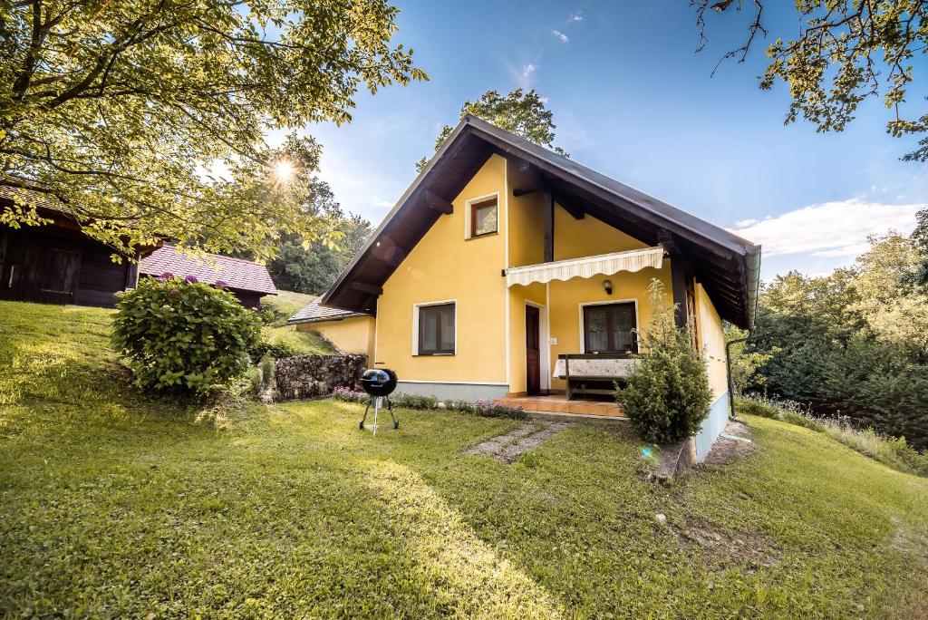 żółty dom z grillem na dziedzińcu w obiekcie Country House Budana w mieście Brestanica