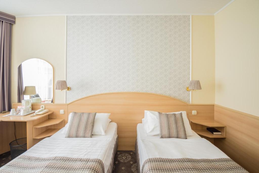 a hotel room with two beds and a desk at Hotel Orion Várkert in Budapest