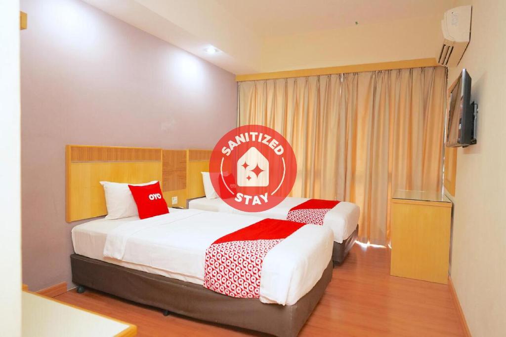a hotel room with two beds and a flat screen tv at Houz Inn in Bintulu