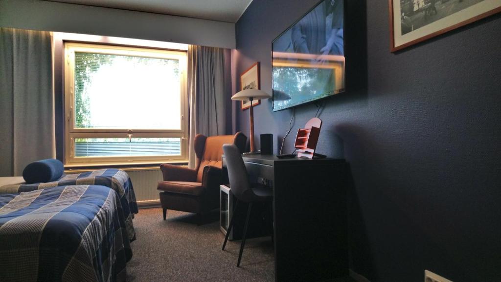 una camera d'albergo con scrivania, letto e finestra di West Side Hotel a Turku