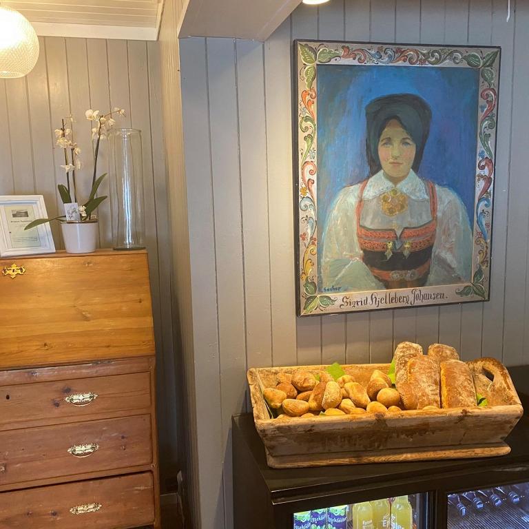 a painting of a woman on a wall with a basket of bread at Bergtun Hotell in Valle