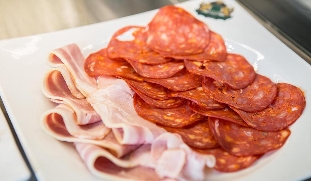 a plate of bacon and meat on a table at Pensiunea Junior in Cluj-Napoca