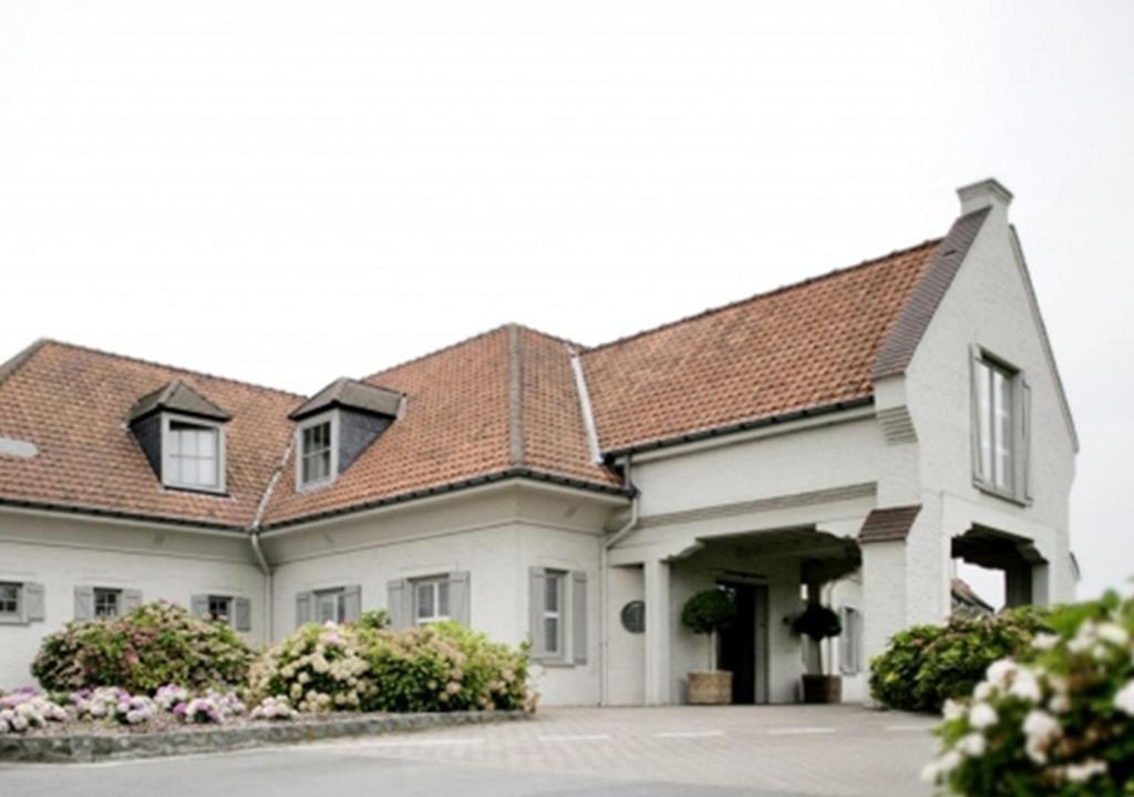 une grande maison blanche avec un toit marron dans l'établissement Hostellerie Klokhof, à Courtrai