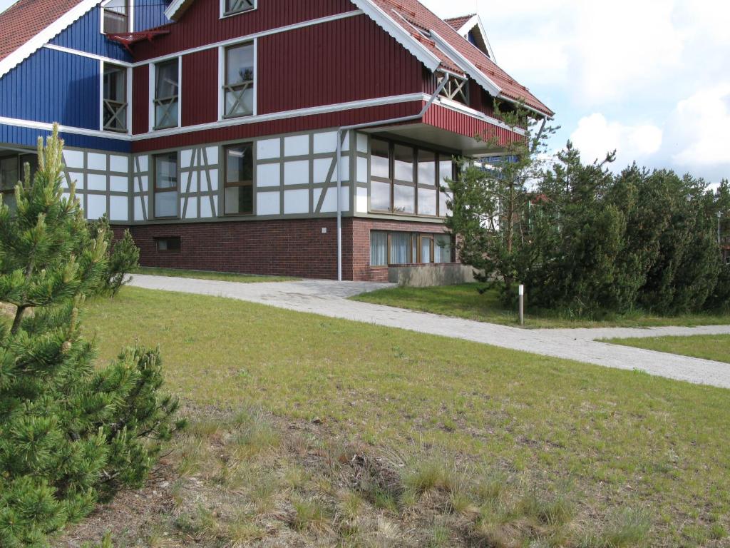 a red and white house with a grass yard at Nidos Poilsine Studio in Nida