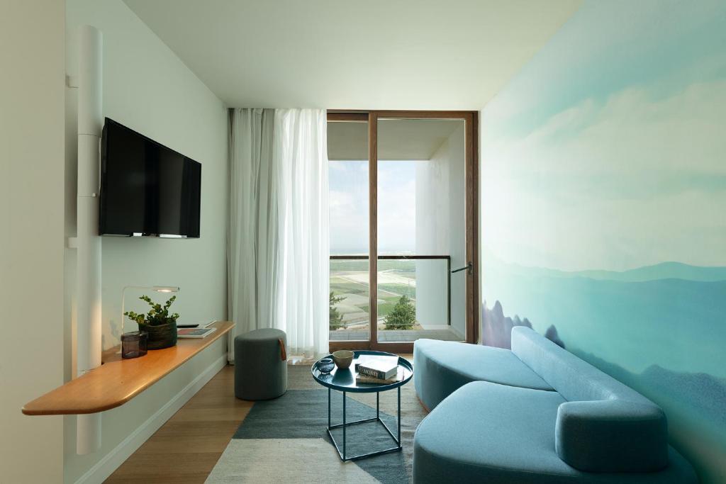 a living room with a blue couch and a window at Elma Hotel and Art Complex in Zikhron Ya'akov