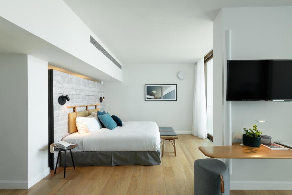 a bedroom with a bed and a flat screen tv at Elma Hotel and Art Complex in Zikhron Ya'akov