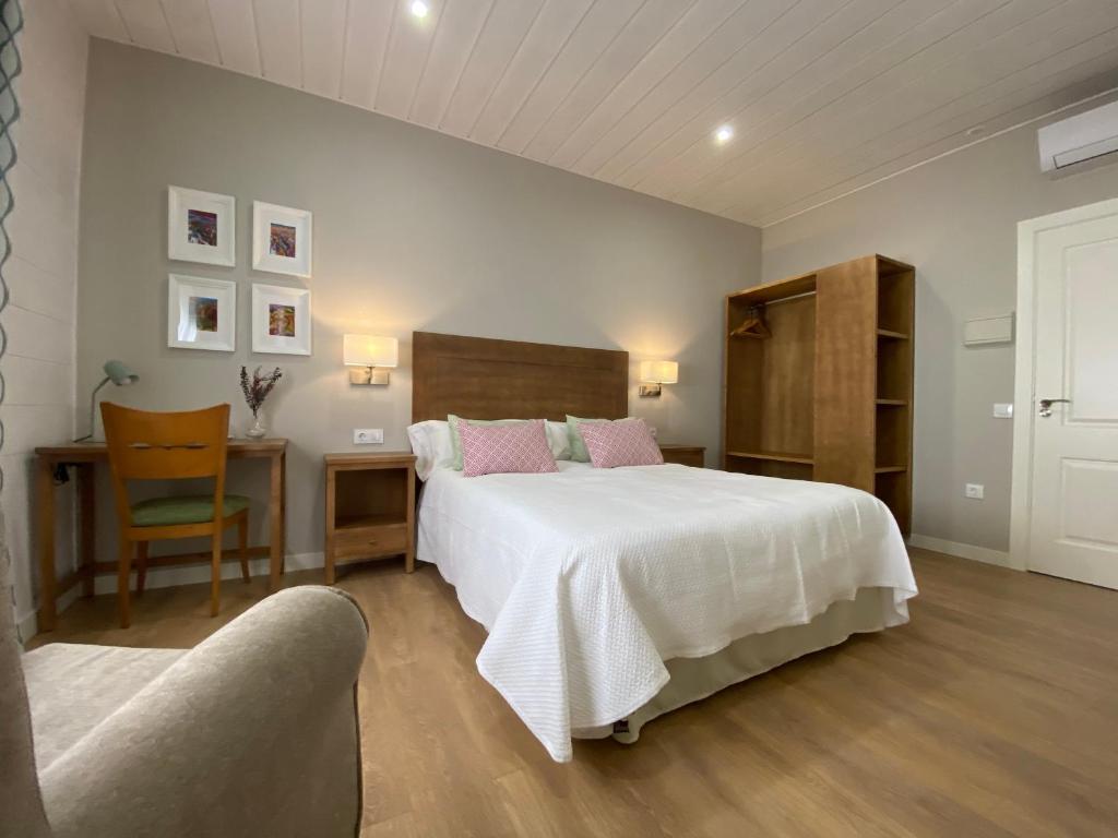 a bedroom with a large white bed and a chair at Azafrán Consuegra in Consuegra
