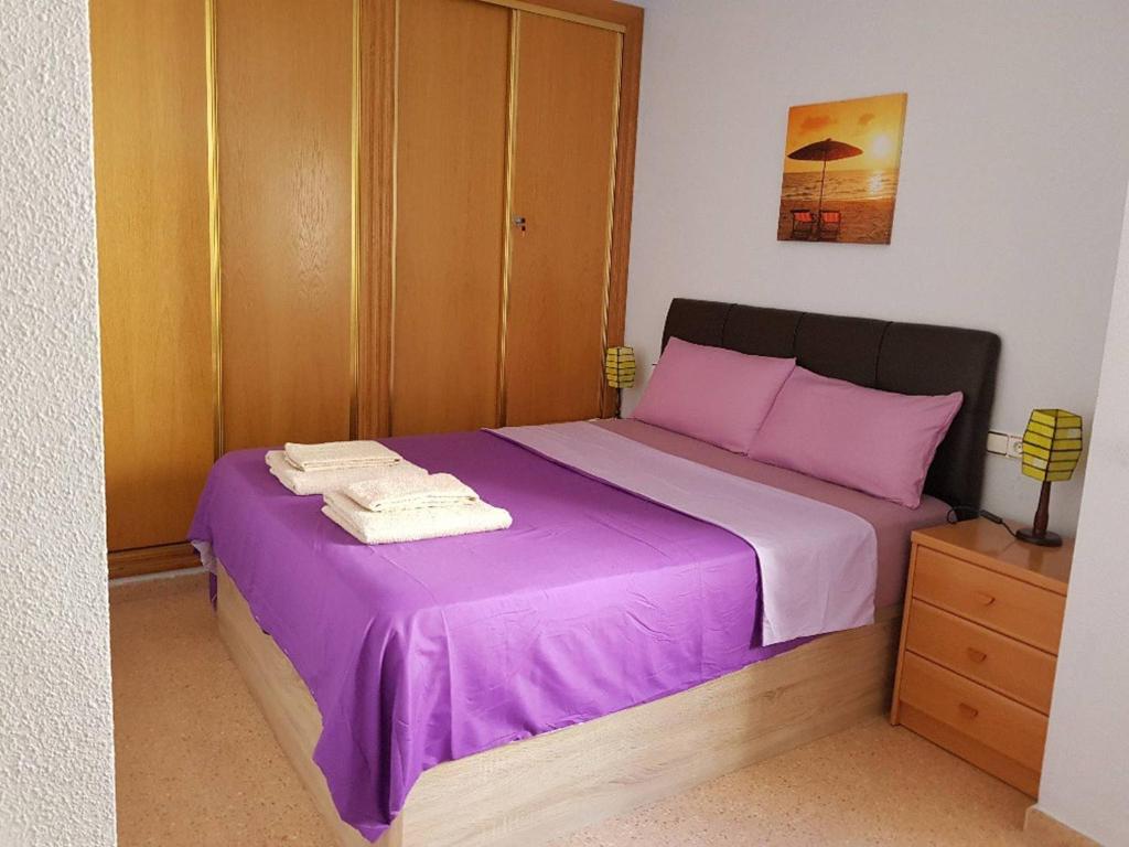 1 dormitorio con cama morada y armario de madera en Nice Apartment Downtown - 2, en Torrevieja