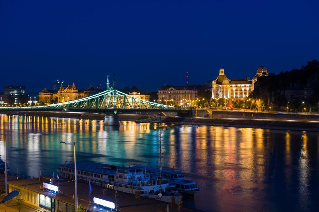 a bridge over a river at night with buildings at Hotel Vision Budapest by Continental Group in Budapest
