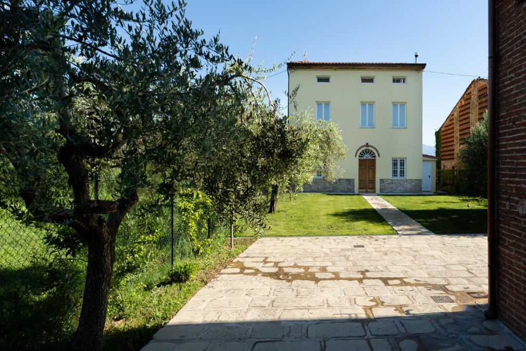 un camino de ladrillo que conduce a una casa con un árbol en Villa Galgani, en Lucca