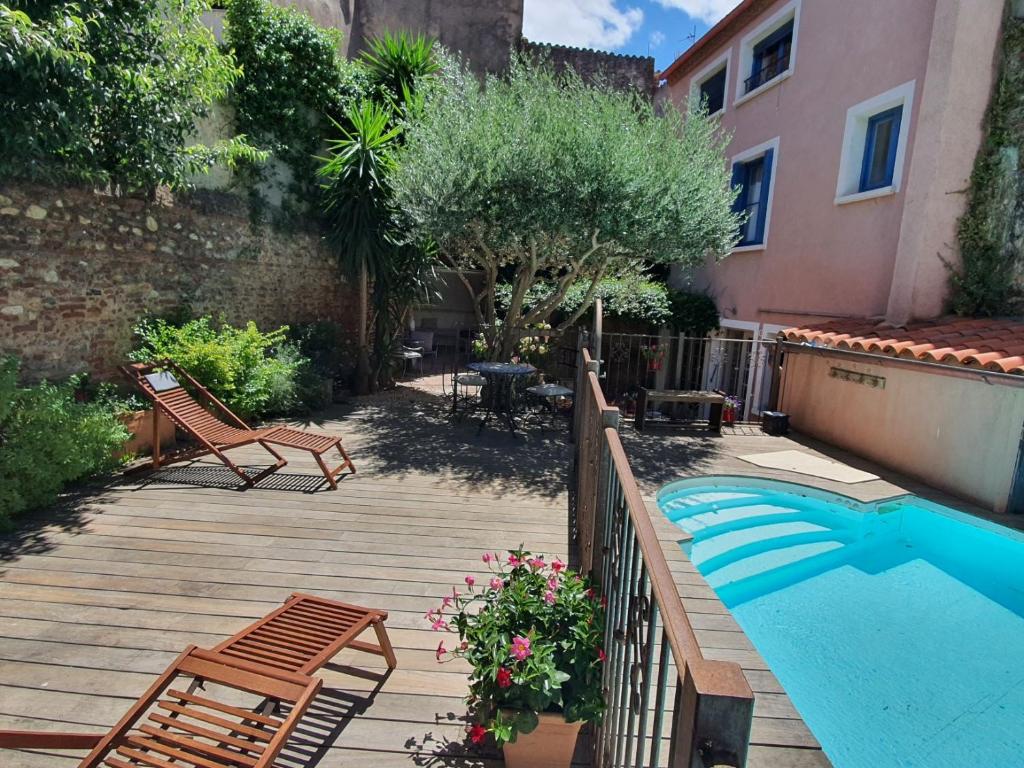 a backyard with a swimming pool and two chairs at Chambres d'hôtes Can Oliba in Elne