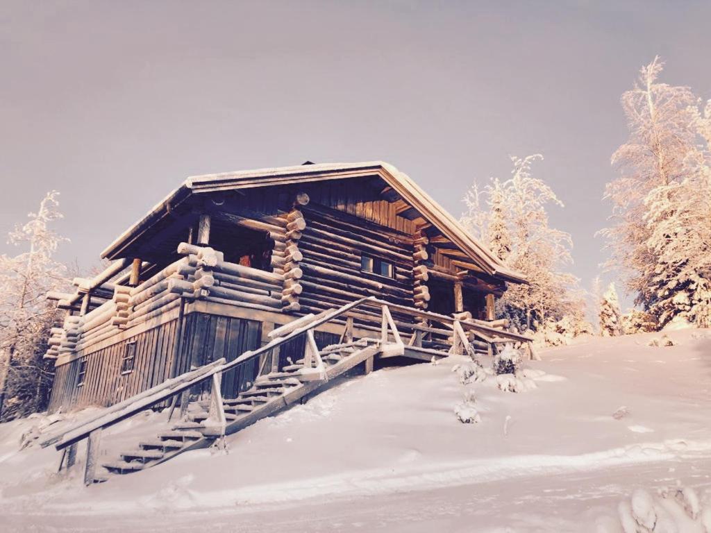 uma cabana de madeira na neve com uma escada em Villa Valtavaara em Ruka