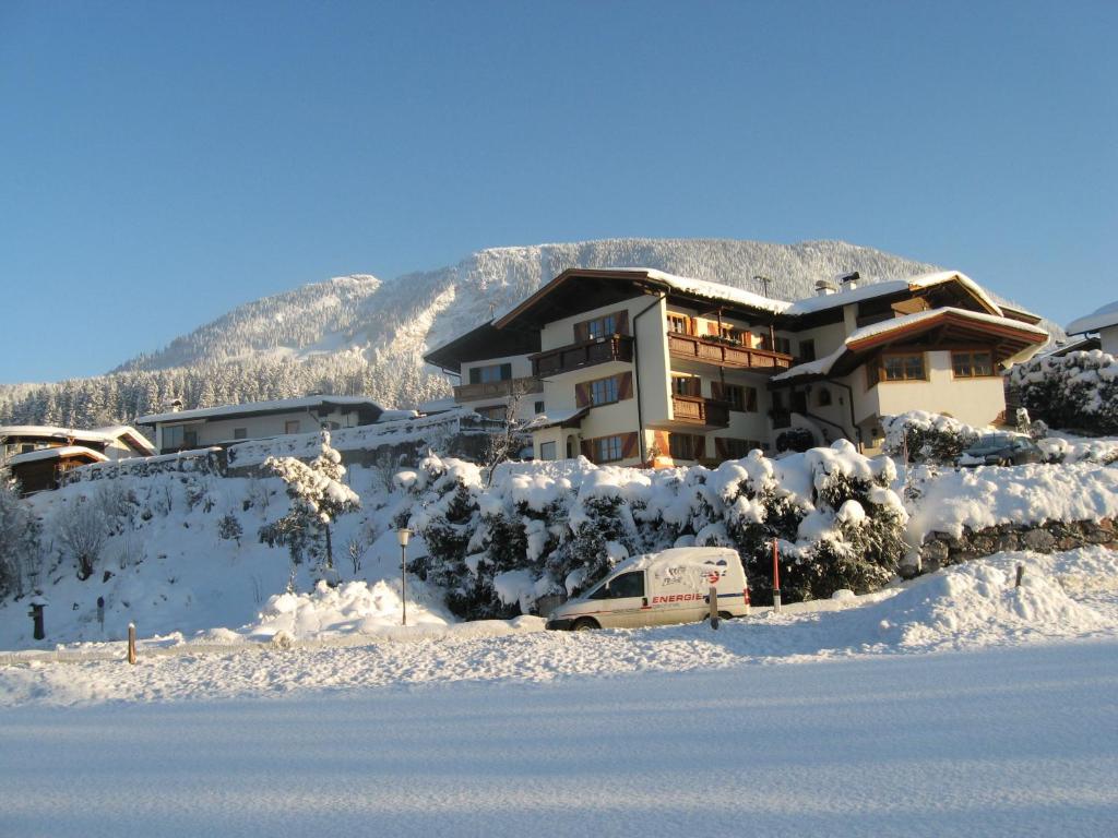 a house with a car parked in the snow at Gästehaus Trude Waltl in Fieberbrunn