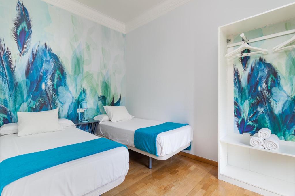 2 camas en una habitación con un mural en la pared en Art House Station Rocafort ´Sant Antoni´, en Barcelona