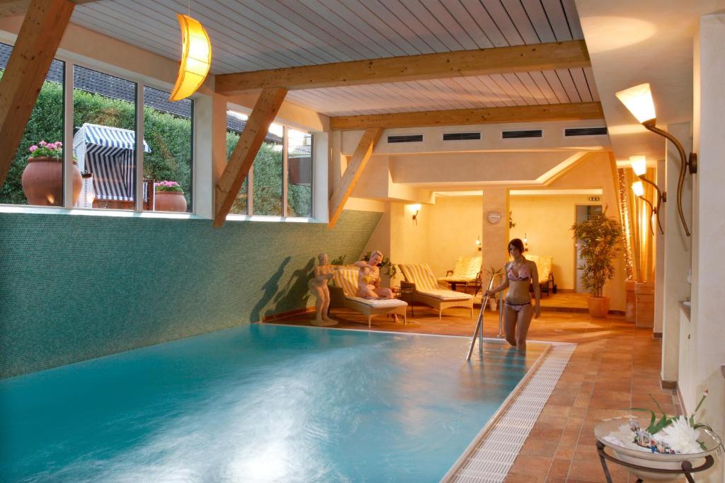 uma mulher está ao lado de uma piscina em Wellness Hotel Harms em Bad Nenndorf