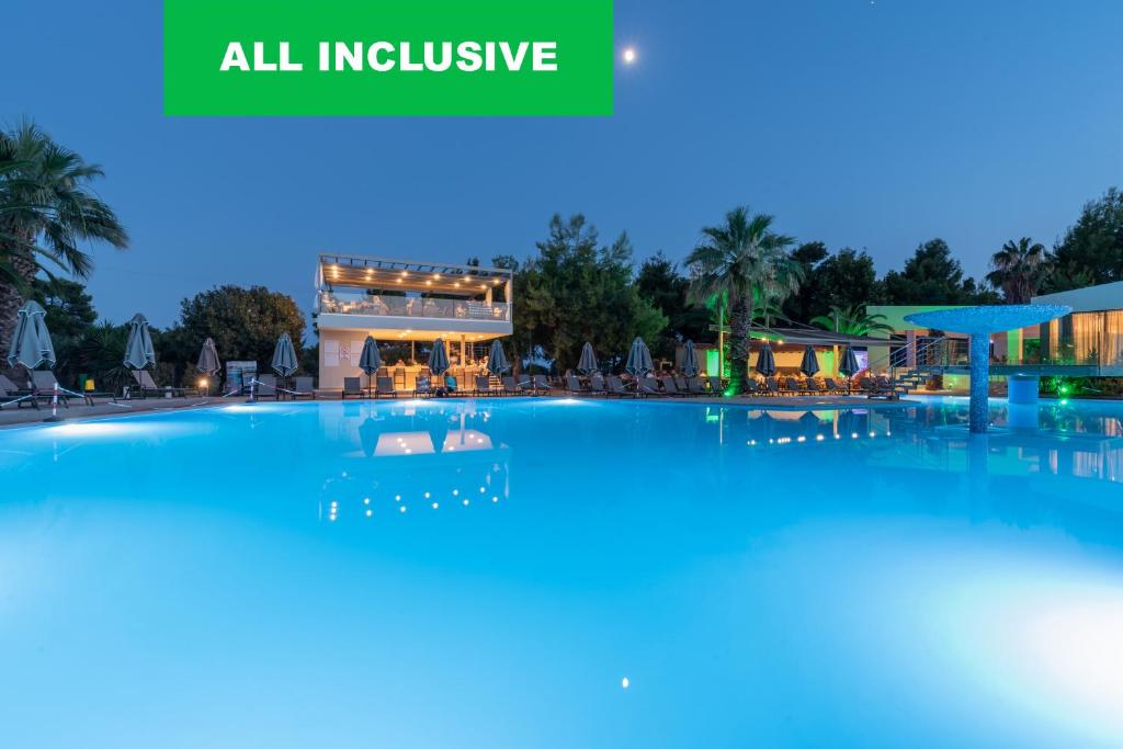 a large swimming pool with a hotel in the background at Poseidon Resort Hotel in Neos Marmaras