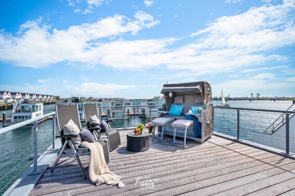 a deck with chairs and a table on the water at Bora in Olpenitz