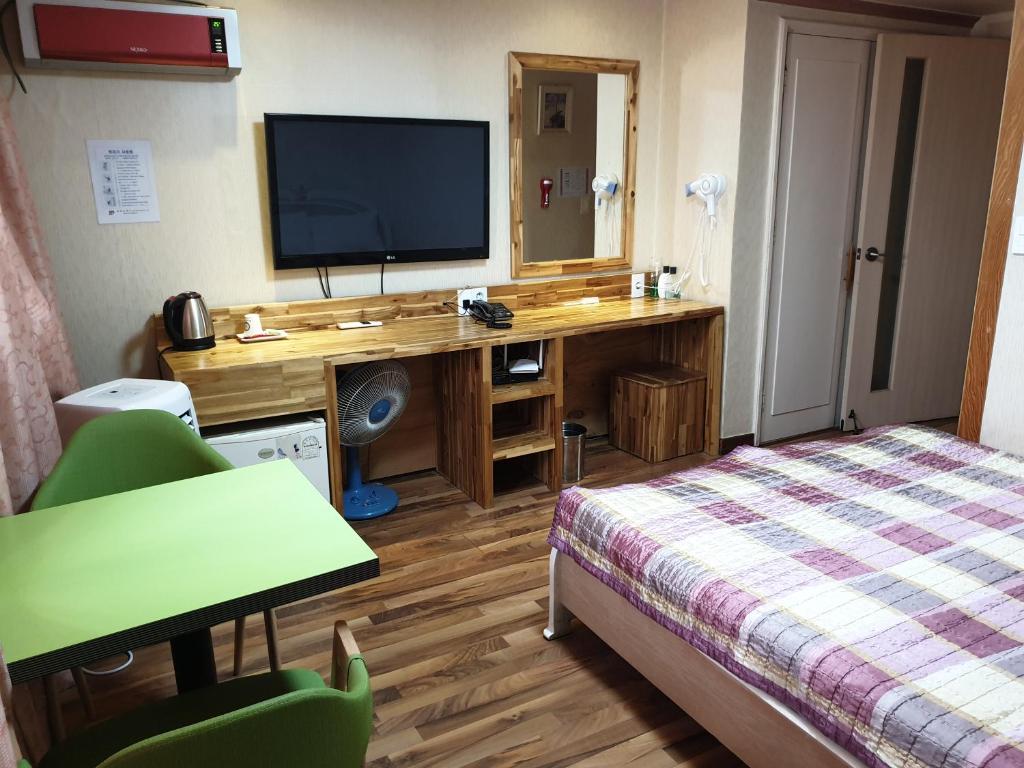 a hotel room with a bed and a desk with a television at Green and Blue Hotel in Pyeongchang