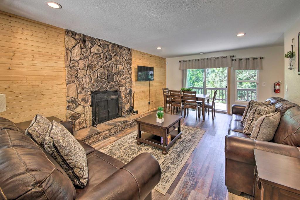 sala de estar con muebles de cuero y chimenea de piedra. en Quiet Lake Arrowhead Retreat with Large Deck!, en Lake Arrowhead