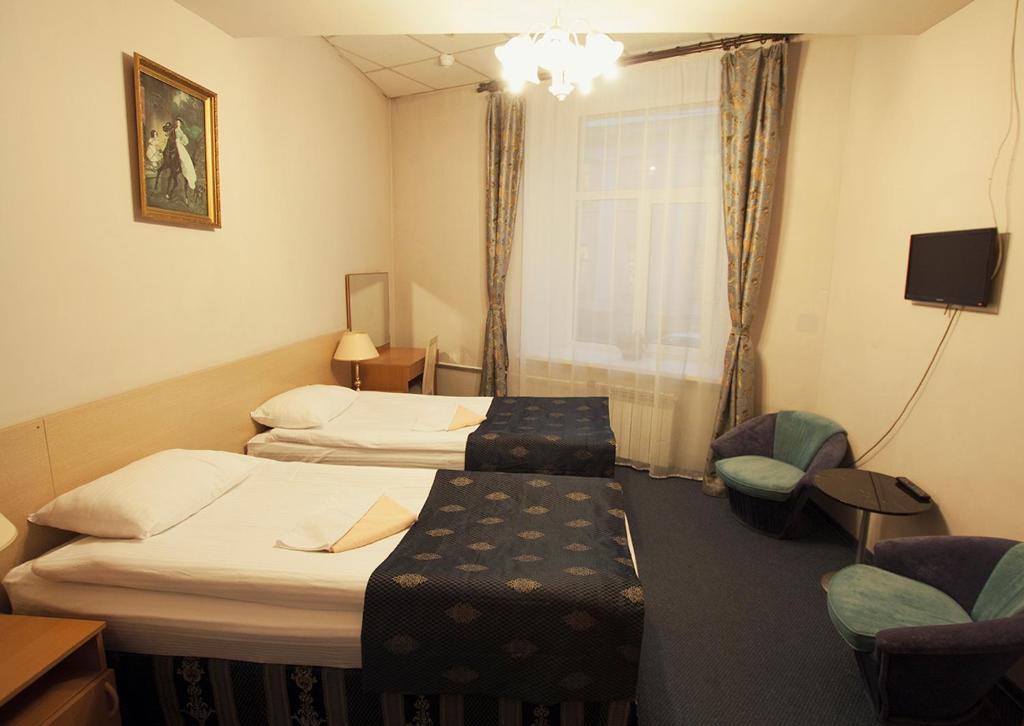 a hotel room with two beds and a chair at Ciniselli Circus Hotel in Saint Petersburg