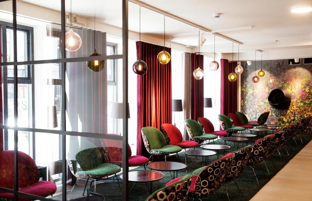 eine Reihe von Tischen und Stühlen in einem Zimmer mit Fenstern in der Unterkunft Andersen Boutique Hotel in Kopenhagen
