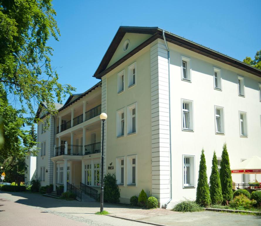 a large white building with a black roof at Impresja Art Resort in Duszniki Zdrój