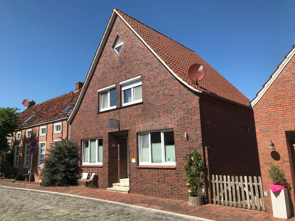 a red brick house with a white fence at Vier Sterne am Hafen, Ditzum in Ditzum