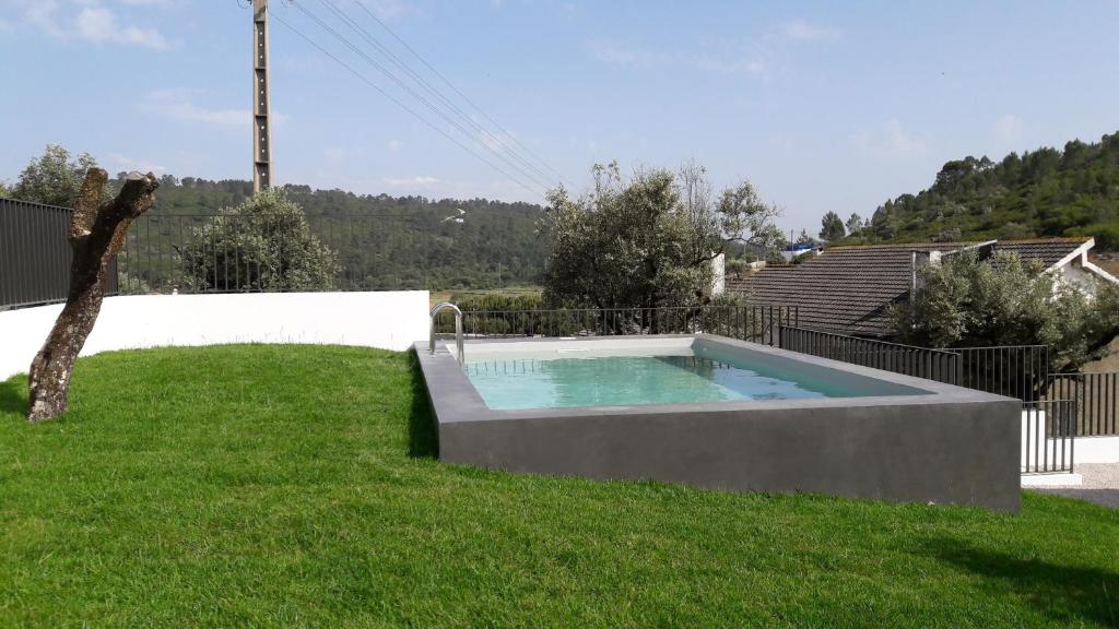 
a pool in a grassy area next to a building at Hostel Pia do Urso in Batalha
