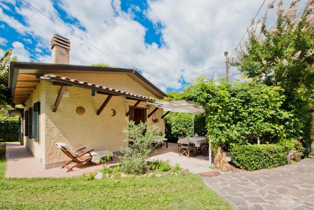 ein kleines Haus mit einer Terrasse und einem Sonnenschirm in der Unterkunft La casina del Mare in Marina di Massa