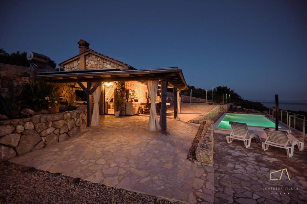 a backyard with a swimming pool and a house at Heritage Stonehouse Jure in Krk