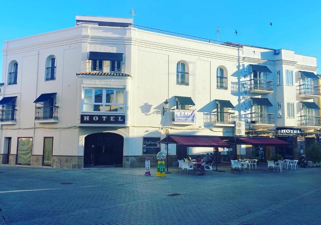 un gran edificio blanco con mesas y sillas delante de él en Hotel La Encomienda, en Moraleja