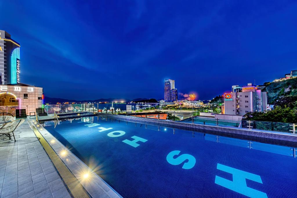HS Tourist Hotel في يوسو: مسبح على سطح مبنى في الليل