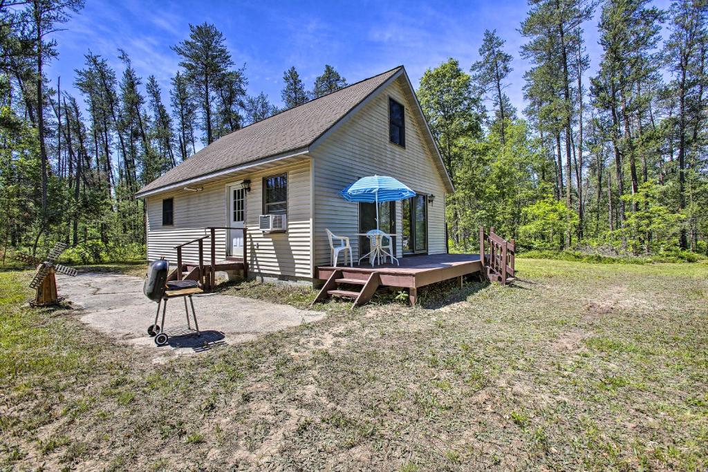a small house with a table and an umbrella at Secluded Irons Cabin with 5-Acre Yard, Deck, Grill! in Irons
