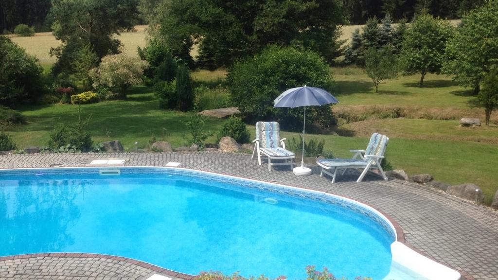 una piscina con 2 sillas y una sombrilla en Forest Paradise en Stružná