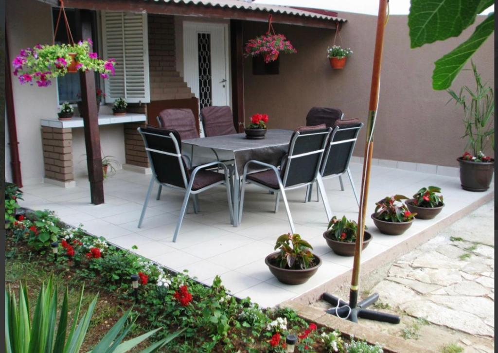 patio ze stołem, krzesłami i doniczkami w obiekcie Apartman Andja sea and garden view w mieście Peroj