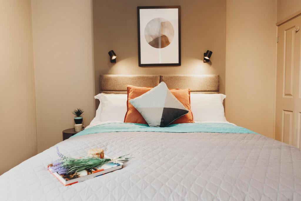 a bedroom with a white bed with orange pillows at Victoria Apartments Tamworth in Tamworth