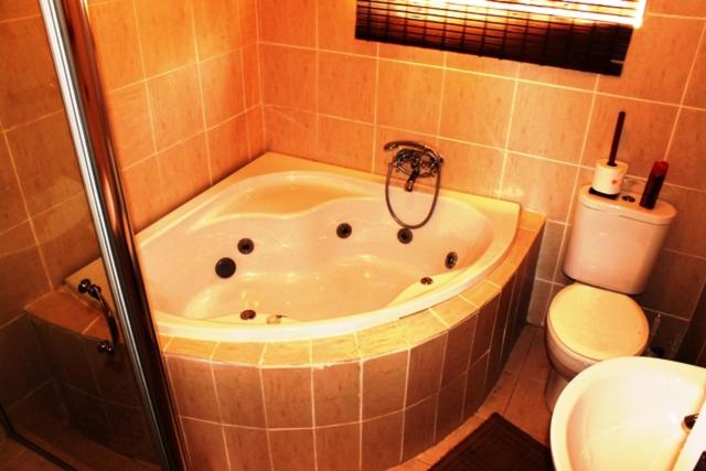 a bath tub in a bathroom with a toilet at Flintstones Guest House Durban in Durban