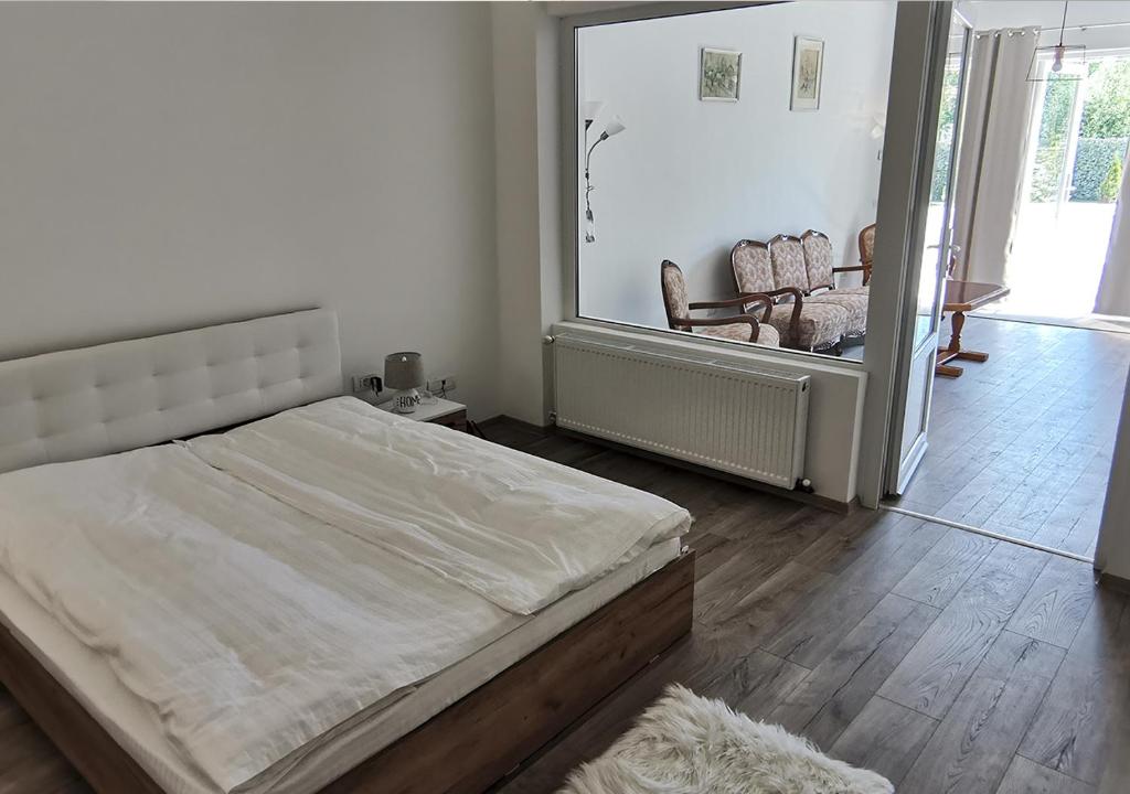 a white bedroom with a bed and a chair at Neferprod Apartments - IS - CAM 07 in Timişoara