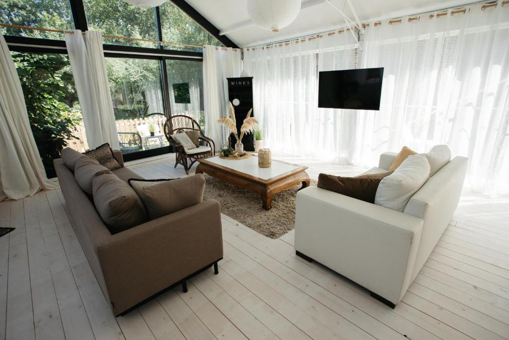 - un salon avec deux canapés et une télévision dans l'établissement Vakantiewoning Loft Lisse - SAUNA - Beach - Keukenhof, à Lisse