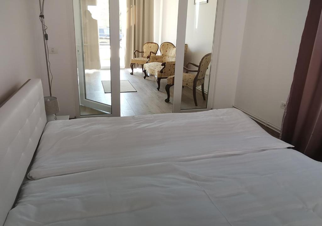 un letto bianco in una stanza con specchio di Neferprod Apartments - IS - CAM 08 a Timişoara