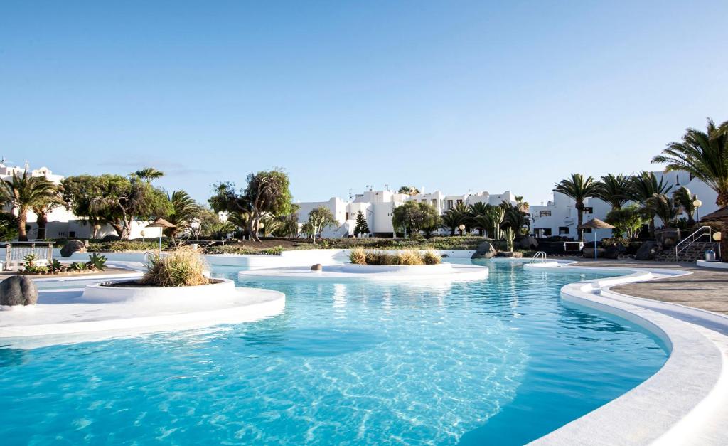 basen w ośrodku z palmami i budynkami w obiekcie Lanzahost Casita El Molino w Costa Teguise