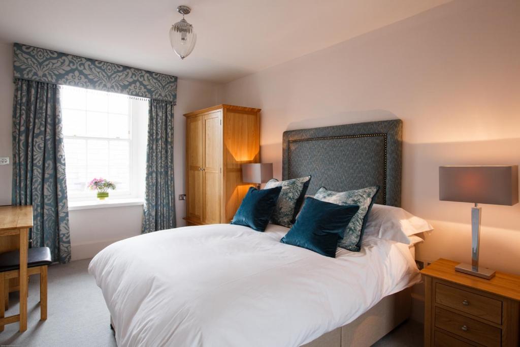 a bedroom with a large white bed with blue pillows at Cardigan Castle in Cardigan